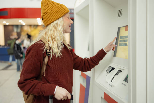 istock Smiling woman buying train ticket at self service machine. 2149791394
