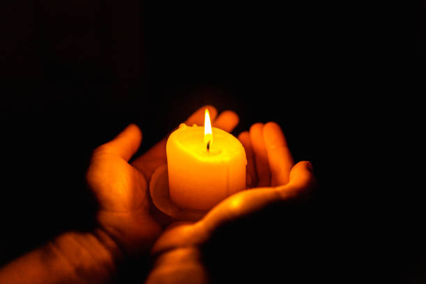 Burning candles in the boy hands on a dark background.Religious concept.