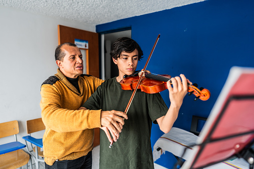 Instructor teaching boy to play violin at class