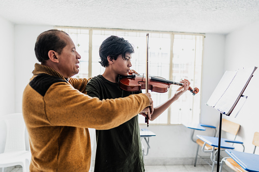 Instructor teaching boy to play violin at class