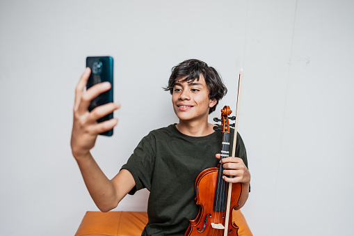 Violinist boy taking a selfie at home