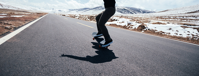Skateboarder skateboarding on snowy country road