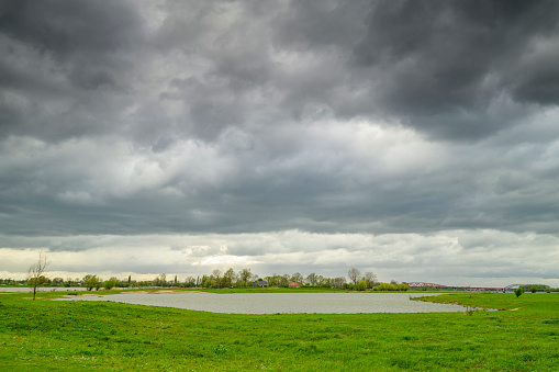 IJssel river with high water level on the floodplains of the river IJssel near Zwolle with dark storm clouds above.