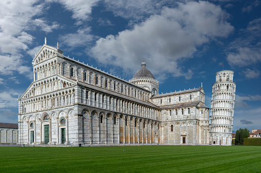 Pisa, Italy - April 05, 2024: landscape of Piazza dei Miracoli with Pisa Cathedral and the Leaning Tower under a blue sky with white clouds