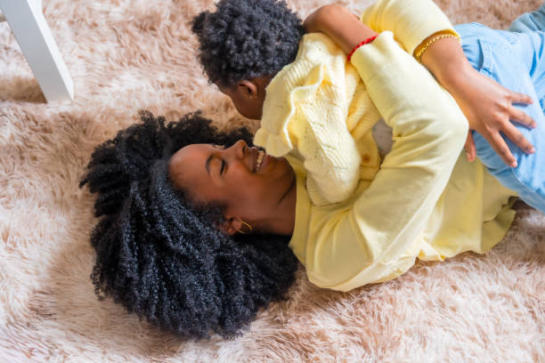 African mother embracing her little girl lying on the floor