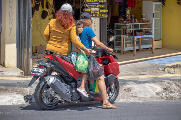 Samosir Island, Lake Toba, North Sumatra, Indonesia - February 1st 2024:  Two women and a child on a motorcycle which is a common way to transport people in Indonesia