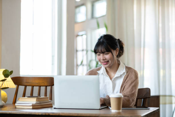 istock Asian students studying online talking together in an online chat meeting using laptops, studying online from home. 2149799743