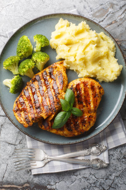 istock Grilled chicken breast served with mashed potatoes and broccoli close-up in a plate. Vertical top view 2149799985
