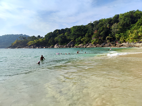 Tourists bathing on the Andaman sea at idyllic Freedom Beach in Phuket, a hidden strip of white sand near Patong, Thailand