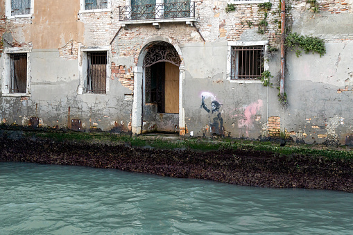 Venice, Veneto, Italy - Jan 23rd, 2024: A Banksy street art piece painted on the walls of an abandoned Venetian palace
