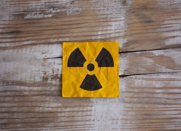 istock A yellow paper note with Radiation warning sign on it on a wooden surface. 2149805528