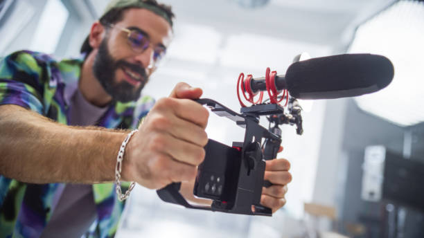istock Focused Young Male Filmmaker With Beard, Adjusting Camera Equipment In Studio, Capturing Content For Advertising Project, Showcasing Diversity And Creativity In Modern Cinematography. 2149805785