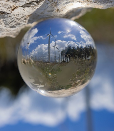 Wind turbine reflected in glass sphere onTechnology green energy concept.