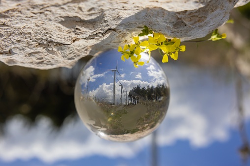 Wind turbine reflected in glass sphere onTechnology green energy concept.