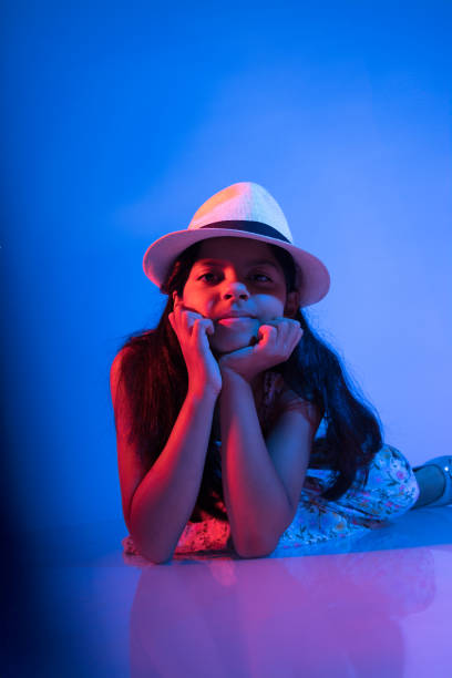 A young girl wearing a white hat is laying on her back with her hands on her knees. She is smiling and she is enjoying herself