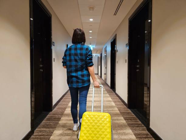 istock Woman Walking Down Hallway With Yellow Suitcase 2149809712