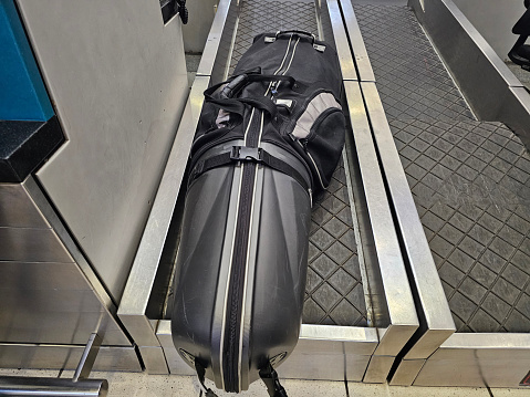A black suitcase is seen placed on top of an escalator, waiting to be transported down or up