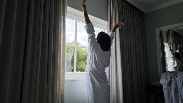 istock Person Reaching Up to Curtain in Room 2149809809