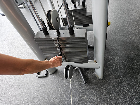 Weight of sports equipment is selected manually. Fitness motivation concept with stack of iron weights for exercise equipment in gym
