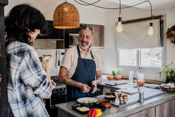 istock Mature man cooking and talking with son in kitchen at home 2149810042