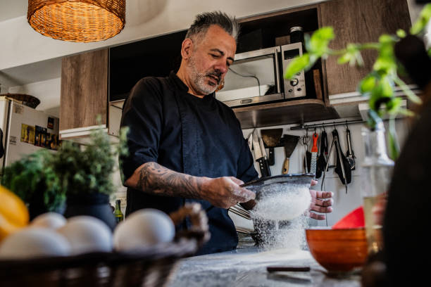 istock Mature man sifting flour in the kitchen at home 2149810753