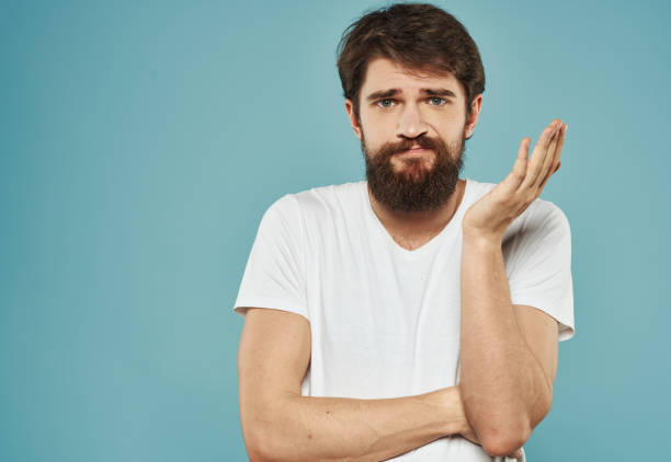istock guy in a white t-shirt on a blue background sad look model Copy Space 2149810999