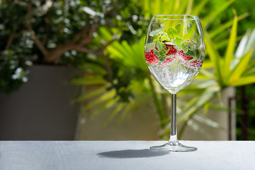 glass of sparkling water with strawberries and mint on the terrace