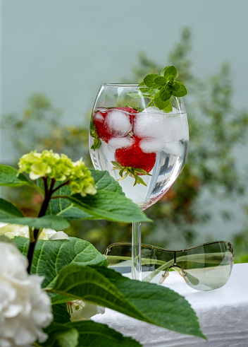 glass of water with strawberries and oregano