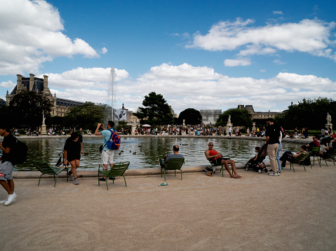 Paris, France - August 13, 2024: People relax by an artificial pond in Paris downtown.
