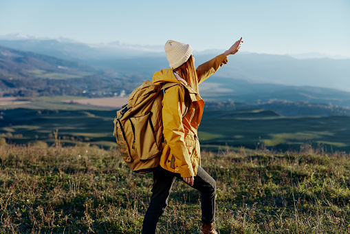 woman traveler in a yellow jacket in a hat backpack travel mountains Lifestyle. High quality photo