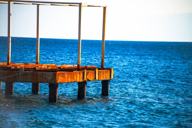 Discover the allure of a weathered, rusty dock standing resilient against the backdrop of the expansive blue sea.