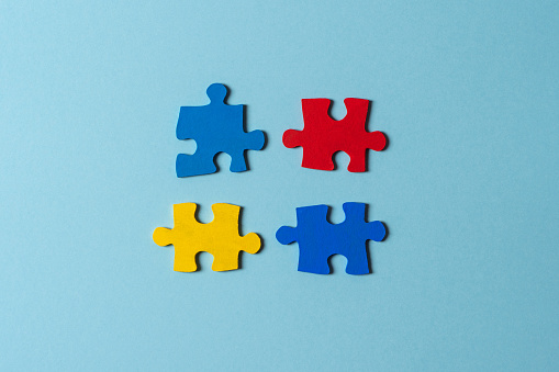 Blue, yellow, red pieces of puzzle on light blue background. World autism awareness day concept. Top view, copy space.