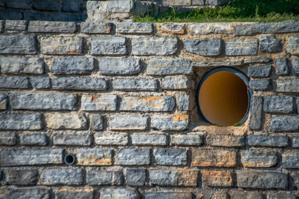 Industrial meets ancient in the juxtaposition of a big pipe against sturdy stone walls, merging modernity with history.