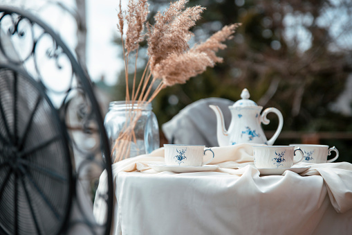 Shabby chic breakfast on balcony . Teapot and cups on a table. Outdoor breakfast on luxury vacation