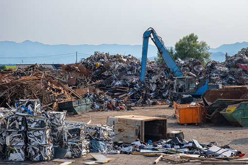 Clow crane picking up scrap metal at recycling center for metal, aluminum, brass, copper, stainless steel in junk yard. Recycling industry. Environment, Earth day and zero waste concept.