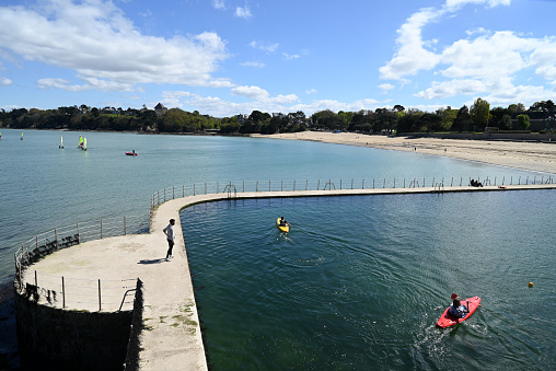 Dinard, France, april 18, 2024 : Kayakers in the Prieuré seawater pool with the Prieuré beach in the background