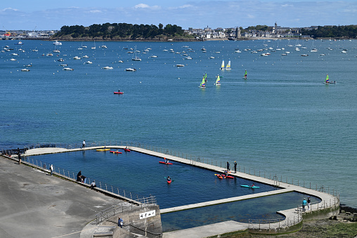 Dinard, France, april 18, 2024 : Kayakers in the seawater pool of the Priory of Dinard with the town of Saint-Servan in the background