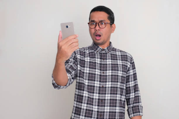 A man looking his mobile phone with shocked face expression