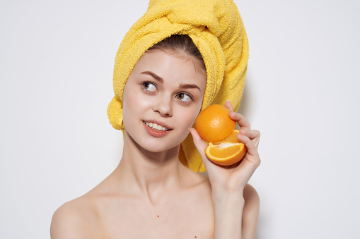 woman with yellow towel on her head bare shoulders fruit orange vitamin. High quality photo