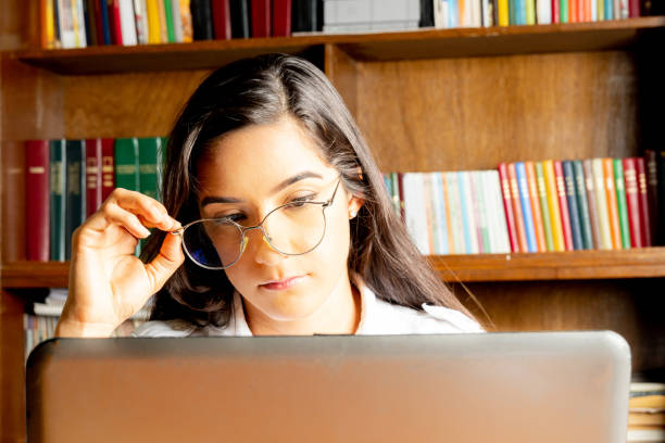 istock young female student with glasses, studying in a library, using a laptop 2149819303