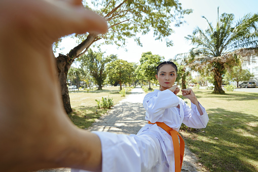Taekwondo athlete in dobok kicking camera