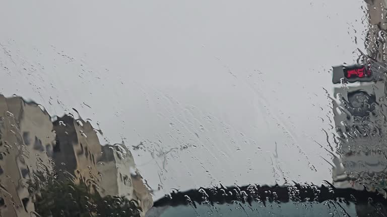 rain drops on window glass over blurred city view , Rain falls in front of the car mirror