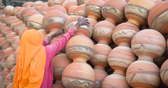 Indian woman arranges clay pots in The Pink City of Jaipur, Rajasthan, India. Jaipur is known as the Pink City, because of the color of the stone exclusively used for the construction of all the structures.