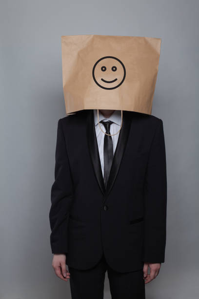 istock Anonymous businessman hiding his head behind happy smile emoticon on gray background 2149823921