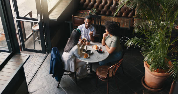 istock Group, colleagues and talking in coffee shop or brainstorming startup idea, planning or collaboration. Man, woman and diversity teamwork with notebook or creative company vision, lunch or discussion 2149825276