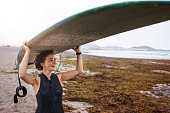 Surfer woman with longboard surfboard at Famara beach in Lanzarote Canary Islands
