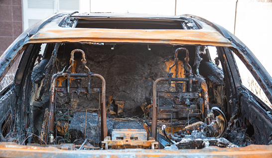 Steering wheel and dashboard of a burnt-out car. The burnt-out interior of the car, a close-up of the fire, extinguishing the fire. A burnt-out car, due to a short circuit, arson, smoke.