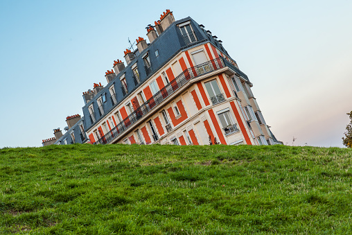 Sinking house on Montmartre hill taken with funny angle, Paris, France at sunset. Optical illusion.