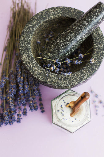 Lavender sugar on purple background, copy space. Granite mortar and pestle with flowers lavender, bouquet of dry lavender and glass jar with lavender sugar