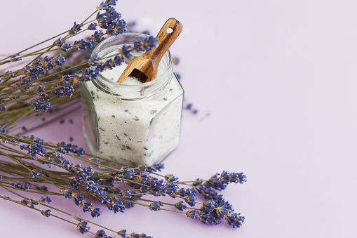 Lavender sugar on purple background, copy space. Bouquet of dry lavender and glass jar with lavender sugar